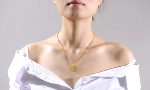 Close-up of a minimalist polished gold coin pendant necklace on a female neck model