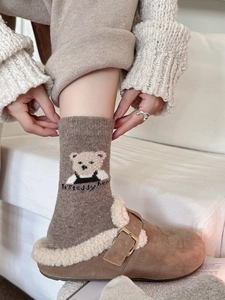 Gros plan de chaussettes en laine avec broderie ours et pantoufles en peluche