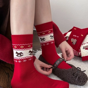 Close-up of red festive cotton socks with knitted rocking horse and geometric patterns