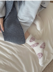 Close-up of coral fleece socks with pink floral pattern and striped knit scarf