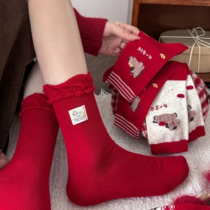 Close-up of red cotton socks featuring intricate horse embroidery and frilled edges