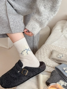 Détail de chaussettes en laine à motif chat avec des mules à boucle en daim gris