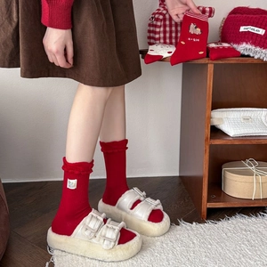 Detail of red knit socks featuring ruffled cuffs and cartoon labels for New Year