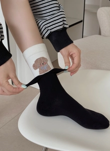 Detail of white cuffed sock featuring a cute teddy bear embroidery and blue bow detail