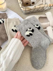 Dettaglio di calze di lana invernali spesse con simpatico motivo a panda in maglia