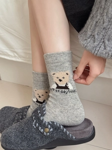 Détail de chaussettes en laine avec motif d'ours en peluche dans un cadre cosy