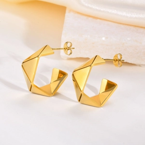 Detail view of gold C-shaped geometric earrings with brushed metal texture and 3D cut