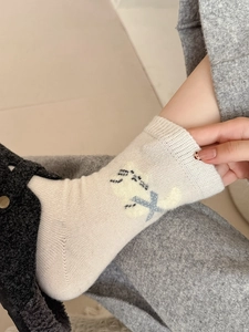 Gros plan sur des chaussettes en laine crème avec motif de chat jaune et tricot doux