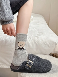 Détail de chaussettes en laine avec broderie ours et sabots en feutre à boucle métallique