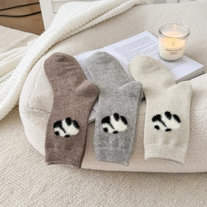 Trama dettagliata delle calze di lana con motivi panda carini in un ambiente accogliente