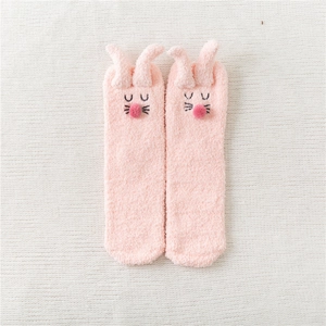 Detail of pink coral fleece slippers socks with cute rabbit ears and plush pom-pom design