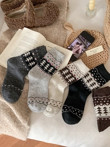 Close-up of Fair Isle knit wool socks featuring winter evergreen and heart patterns