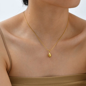 Elegant gold-tone water drop pendant necklace on model wearing beige knitwear