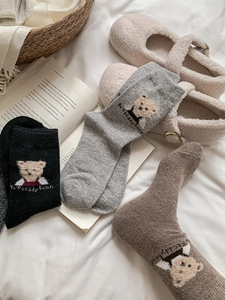 Texture de tricot détaillée des chaussettes en laine avec broderie de petit ours
