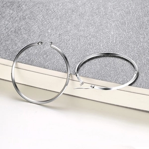 Detail of minimalist oversized silver hoop earrings with a sleek polished metal finish