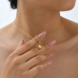 Close-up of a glossy gold water drop pendant necklace on a sleek snake chain for women