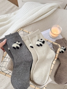 Dettaglio della maglia di calze di lana con simpatico motivo a panda in ambiente caldo