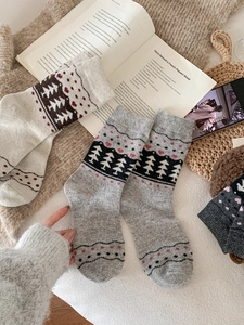 Close-up of cozy wool socks with Fair Isle pine tree and heart patterns on a blanket