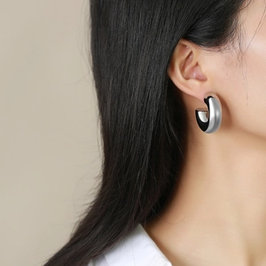 Boucles d'oreilles créoles épaisses en acier inoxydable poli portées par un modèle