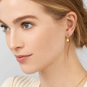 Detailed view of polished golden teardrop earrings on model with high gloss finish