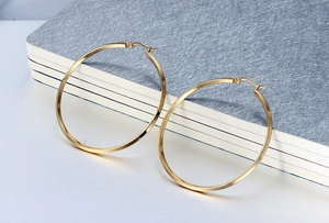 Detail view of large gold hoop earrings placed on a textured blue notebook