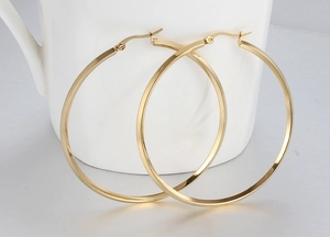 Macro view of large polished gold hoop earrings with a modern square section design