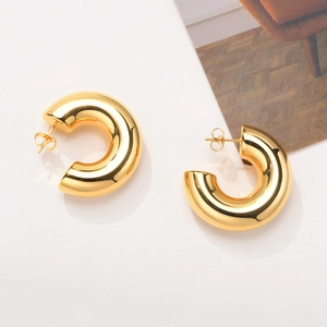 Détail des boucles d'oreilles créoles dorées en forme de C avec fermoir papillon classique