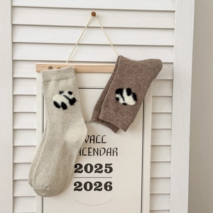 Dettaglio di calze in lana con ricamo panda 3D nei colori beige e marrone
