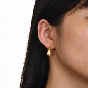 Close-up of golden waterdrop earrings on model showing size and polished finish