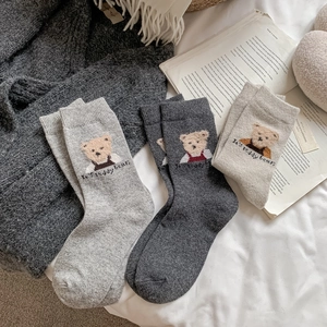 Gros plan de chaussettes d'hiver épaisses en laine avec broderie ours en gris