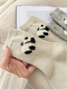 Dettaglio di calze invernali in lana con motivi a zampa di panda e morbida maglia calda