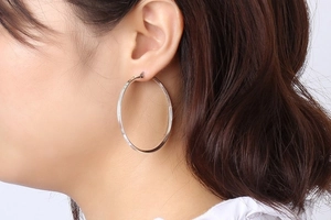 Close-up of model wearing large polished silver hoop earrings in a minimalist style