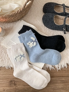 Vue détaillée de trois paires de chaussettes en laine avec motifs de chats et nœuds bleus