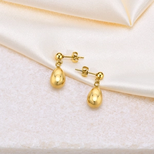 Polished golden teardrop earrings for women made of stainless steel on silk fabric