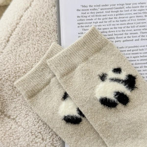 Dettaglio del ricamo panda in peluche su calze di lana beige spesse e calde per l'inverno