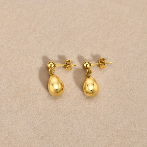 Elegant gold drop earrings with polished round studs and teardrop pendants on beige felt