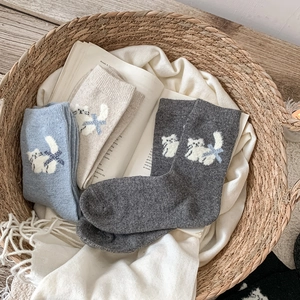 Détail de chaussettes en laine à motif chat dans un panier sur couverture douce