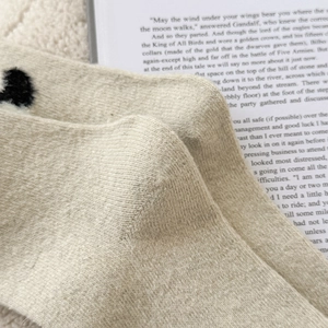 Dettaglio della trama di calze in lana beige con motivo jacquard a cuore nero