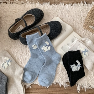 Détail de chaussettes en laine avec motif chat blanc et nœud bleu dans des chaussures