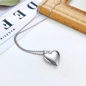 Macro view of polished silver heart locket necklace with glossy finish on white background