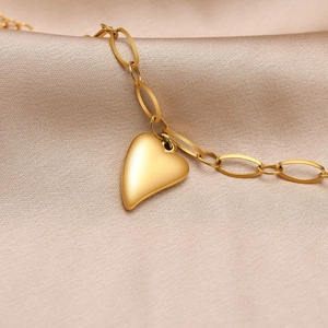 Detail eines Satin-Gold-Herzanhängers an einer Gliederkette auf Seidenstoff