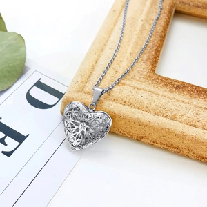 Detailed view of silver heart locket necklace with geometric cutouts on stone frame