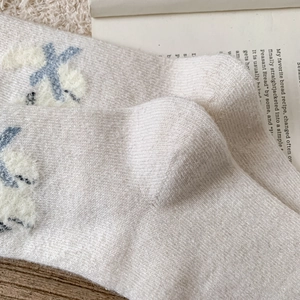Texture détaillée de chaussettes en laine beige avec accents en peluche bleue et maille