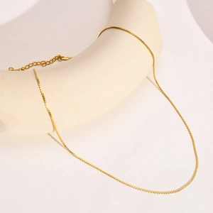 Detail of 18k gold S-chain necklace showing lobster clasp and adjustable extension chain
