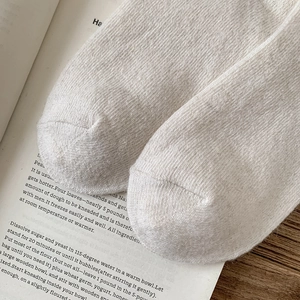 Gros plan de chaussettes blanches en laine montrant la texture du tricot sur un bureau