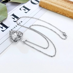 Detailopname van zilveren hartvormige medaillon ketting met levensboom op bladeren