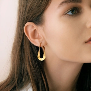 Detailed view of gold Mobius drop earrings on model showcasing polished twisted texture