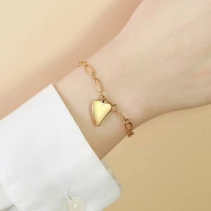Elegantes goldenes Herzanhänger Armband mit ovalen Gliedern am Handgelenk einer Frau