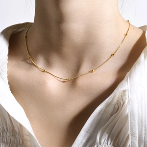 Collier ras du cou doré à perles minimaliste sur mannequin en chemisier blanc
