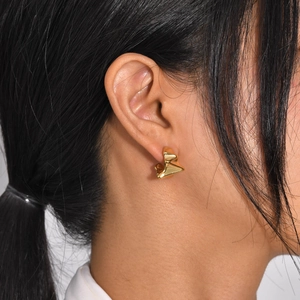 Boucles d'oreilles créoles dorées en C avec texture froissée portées par mannequin